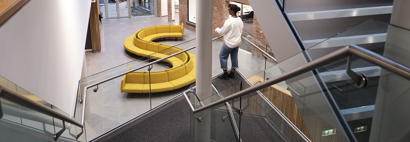 Internal of the Law School Building looking down from mezzanine at yellow sofas and stairs.