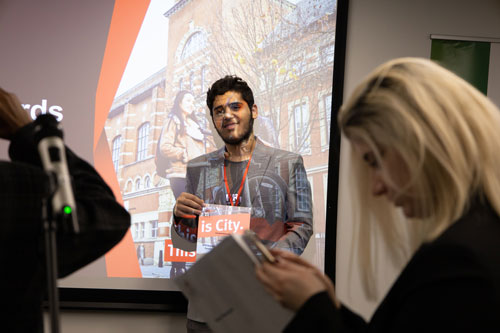 A student poses in front of a screen at the scholarship awards 