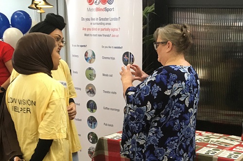 Two City Optometry students talking to a visitor to a stand at the low vision day event at St Thomas' Hospital