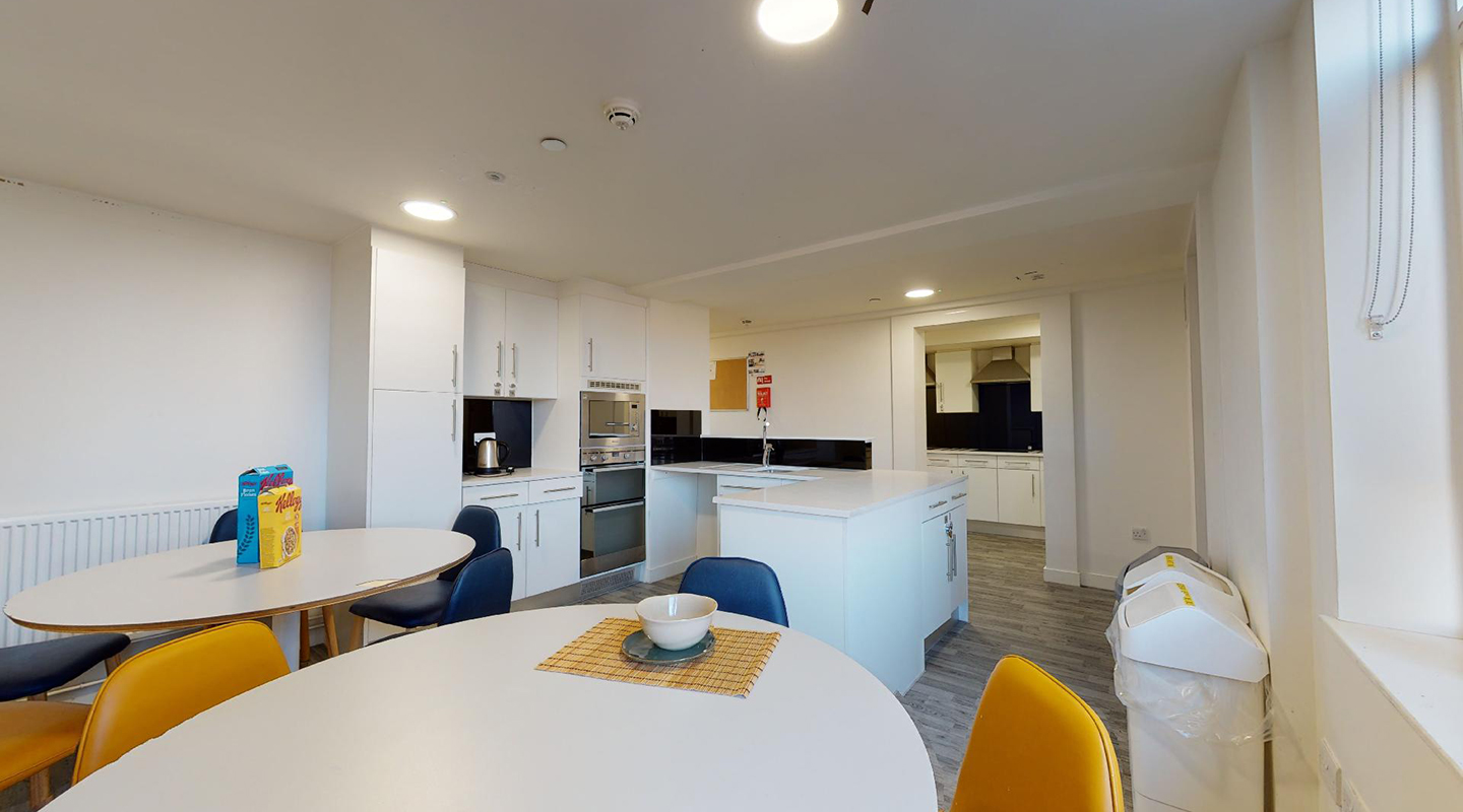 Shared kitchen with two round dining tables and chairs.