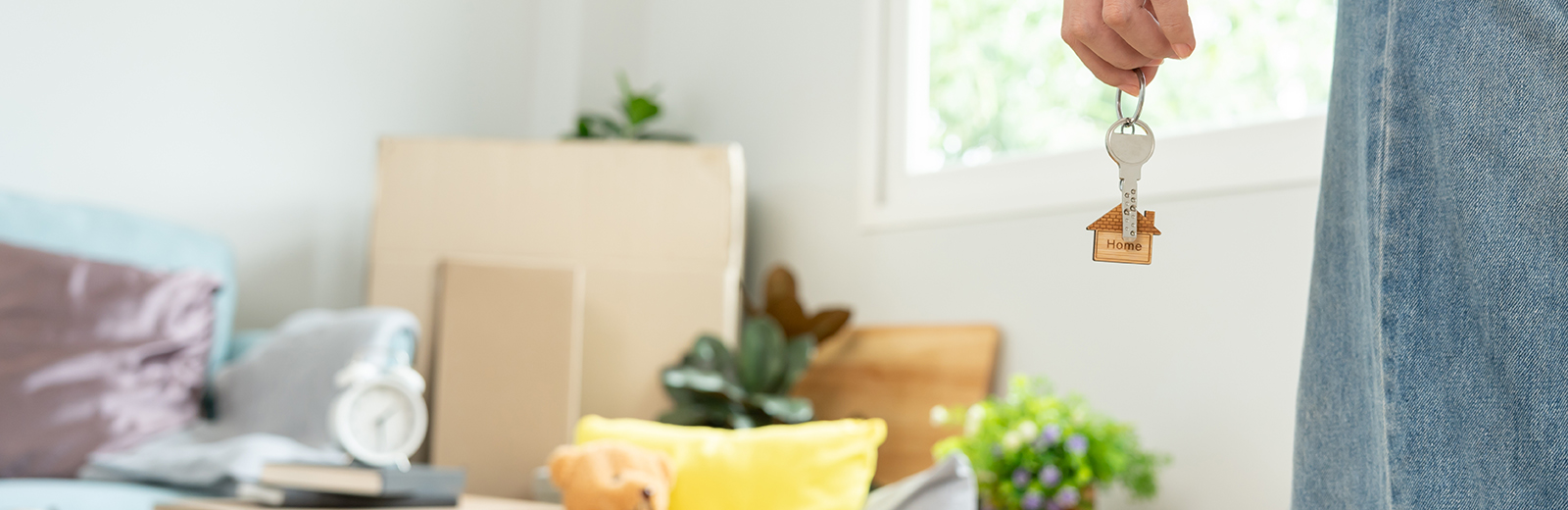 Woman holding keys with possessions in background.