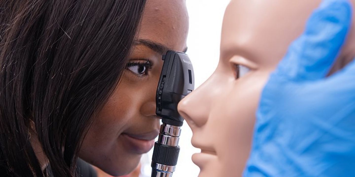 Students looking into the mannequin's eye in clinical skills practice space