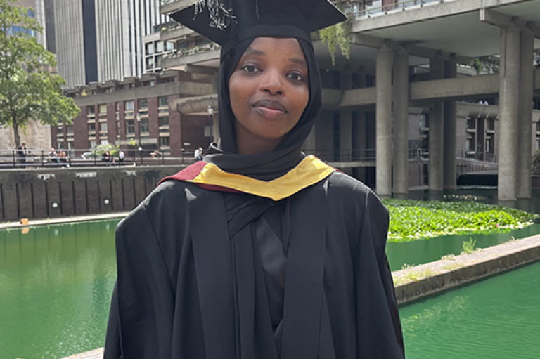 A woman smiles in cap and gown
