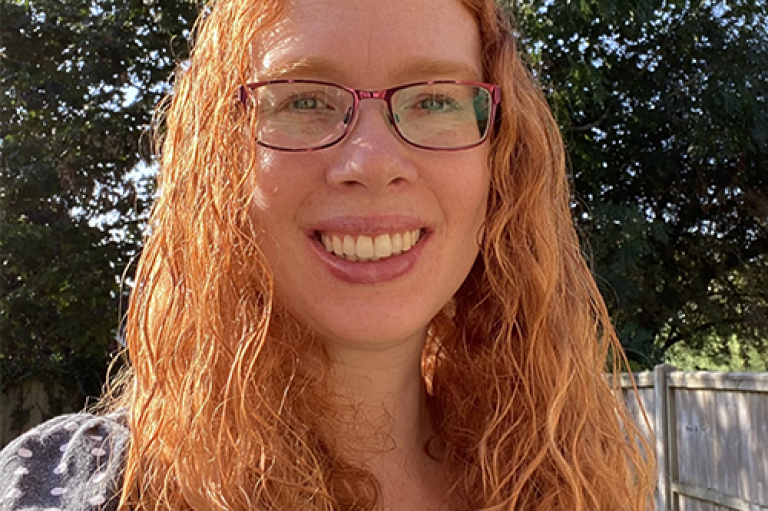 A selfie of a woman in glasses with long curly hair