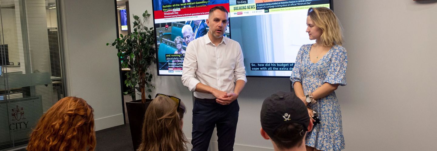 Dr Glenda Cooper and a male colleague presenting during Multimedia Fortnight in the Department of Journalism, speaking to an engaged audience.