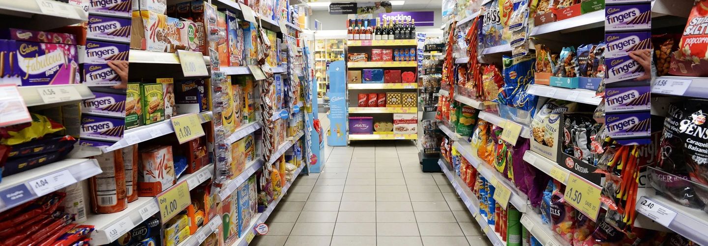 A supermarket aisle filled with snacks, cereals, and discounted grocery items neatly arranged on both sides.