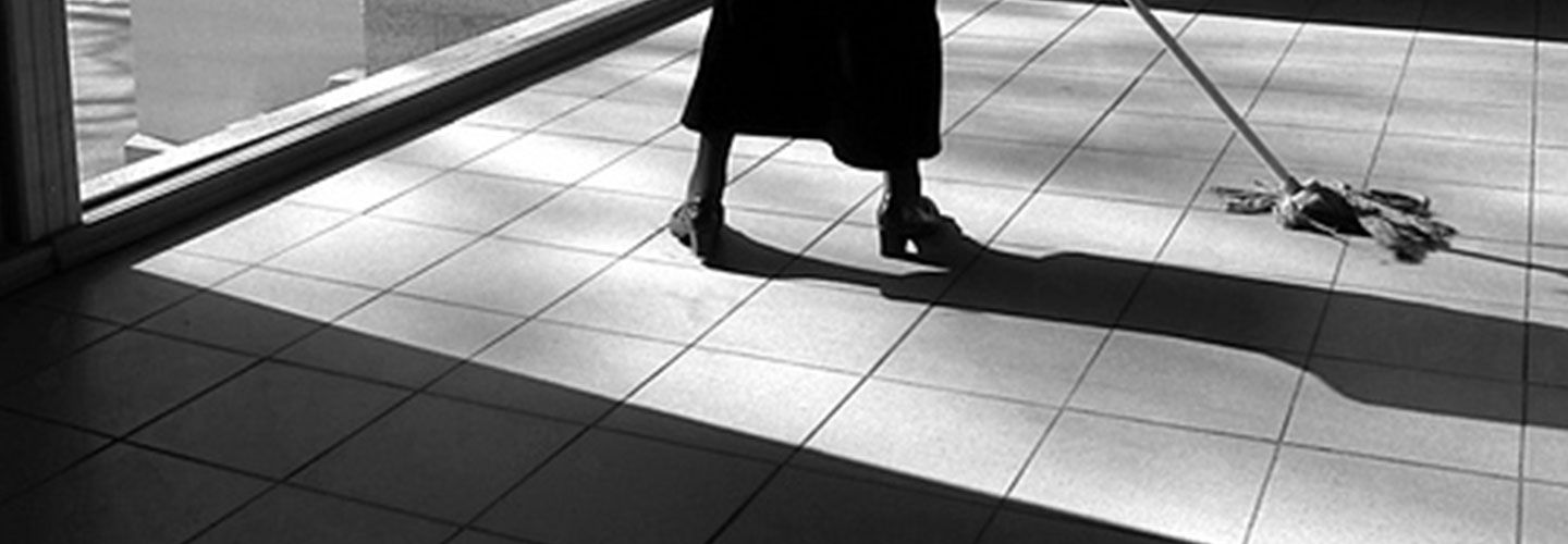A black and white image of a woman mopping tiles