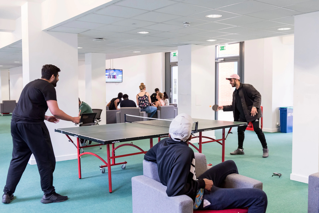 Students gathering in common room, watching TV and playing table tennis