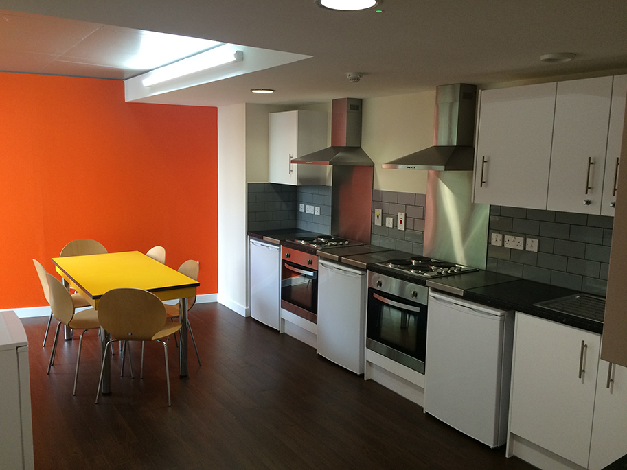 Alliance House shared kitchen featuring yellow table and chairs, from back of kitchen