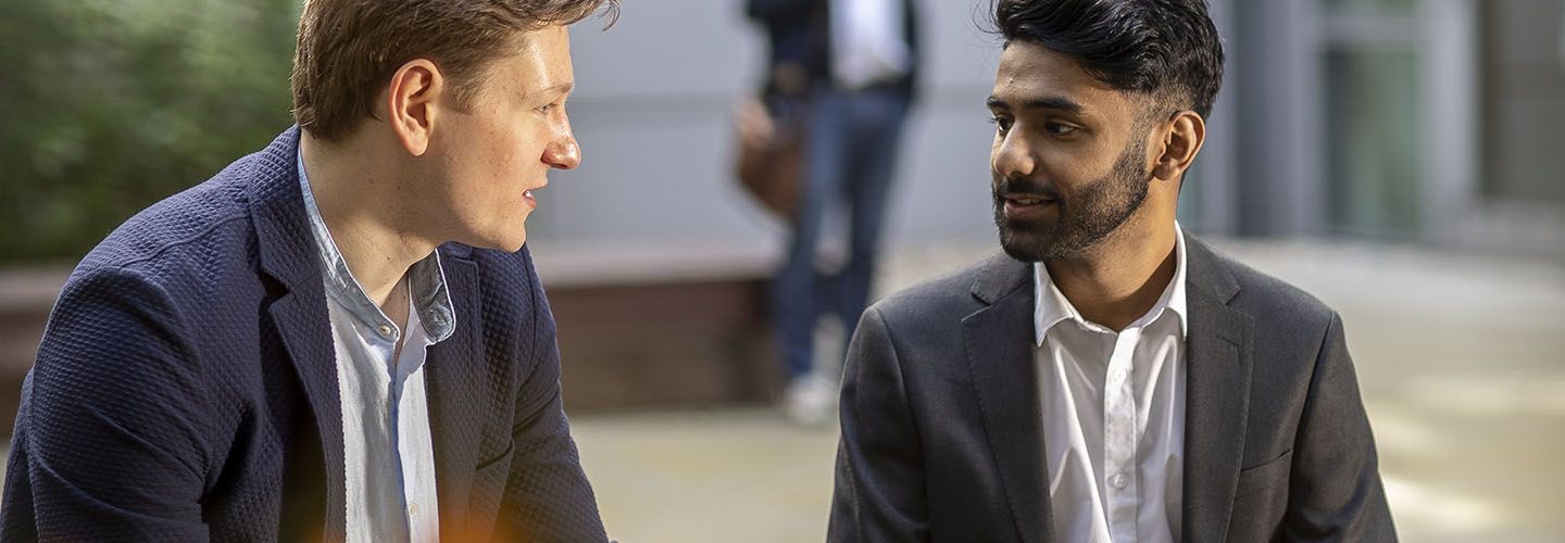 Two male business students in conversation outside the business school.