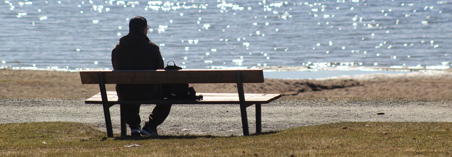 Person sitting in solitude on a bench by the sea