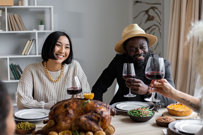 Couple sitting at a dinner table raising a toast with wine glasses.