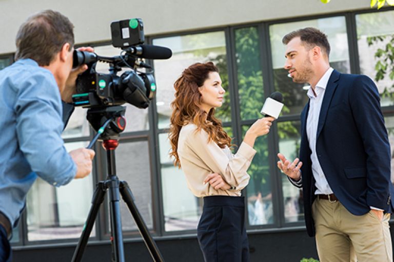A woman interviewing a man on camera.