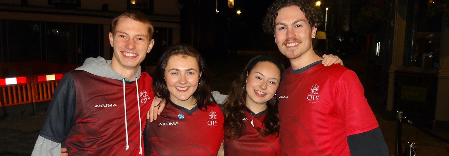 Four hockey co-captains (two men and two women) are smiling and standing together at a pub crawl