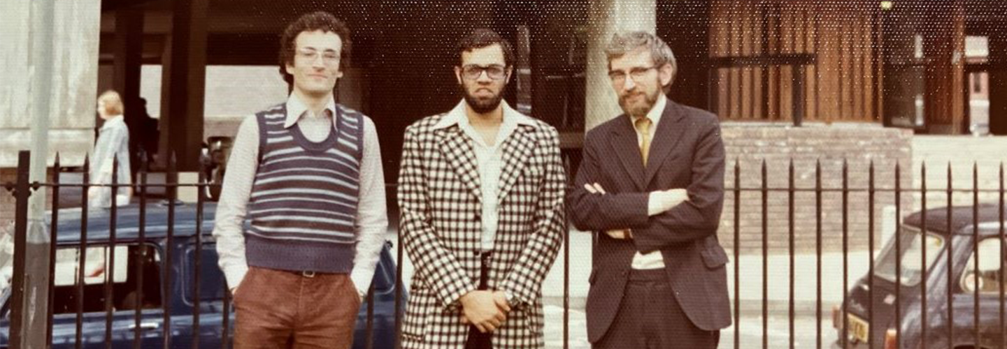 Three men in distinctive 1970s clothing outside Bayes Business School