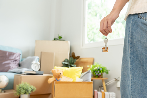 Woman holding keys with possessions in background.