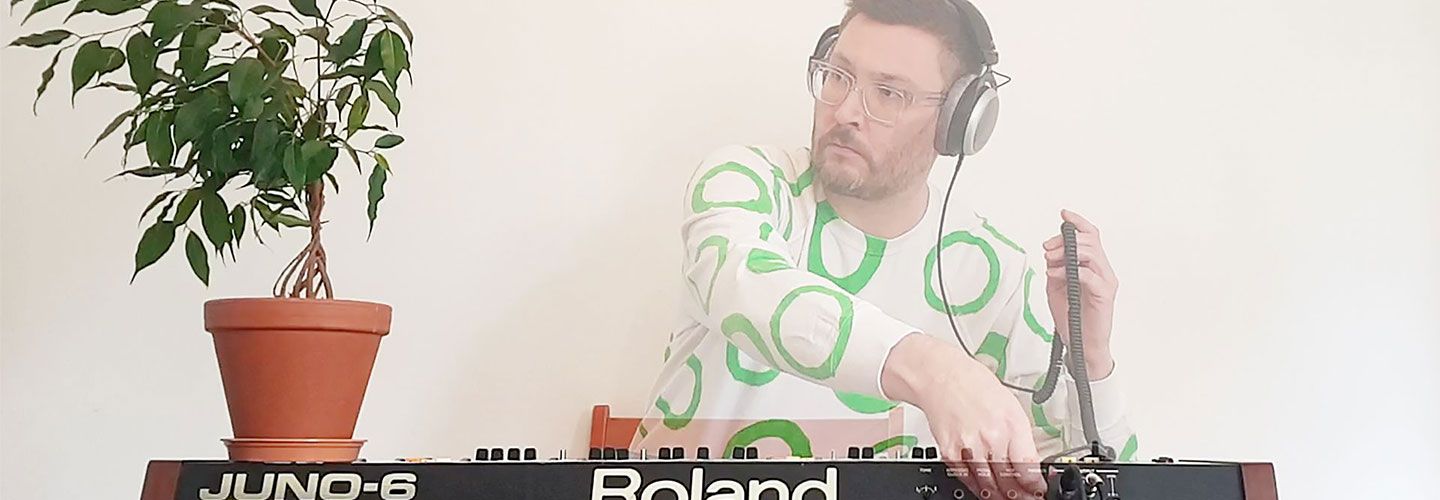 An image of Leo Chadburn, sitting cross legged, playing at a keyboard. He holds a microphone in one hand. There is a pot plant on one side of the keyboard. The keyboard and pot plant are clear, whereas Leo is slightly translucent.