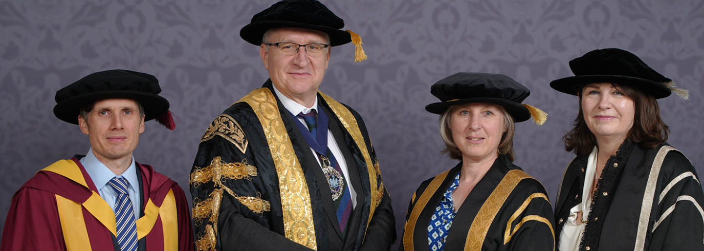 Two men and two women pose wearing doctoral bonnets 