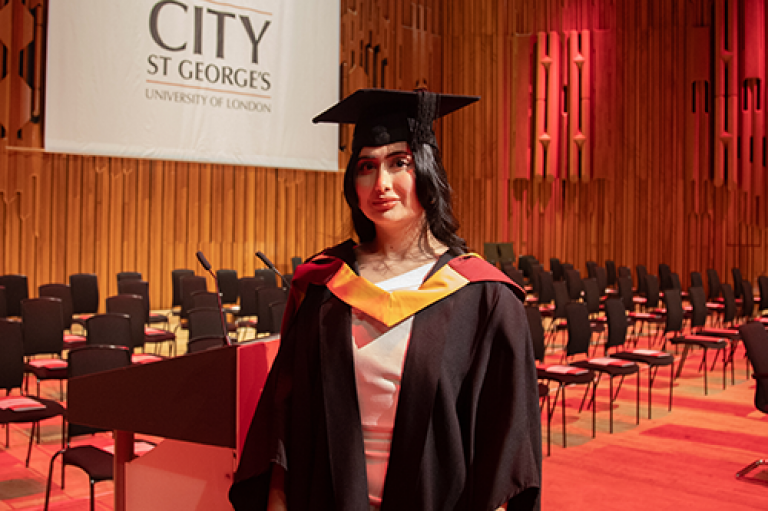 A woman in cap and gown smiles on stage
