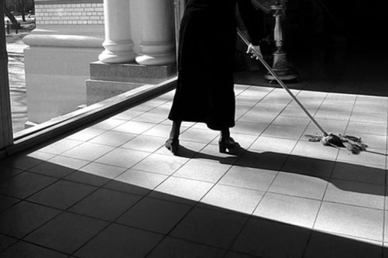 A black and white image of a woman mopping tiles
