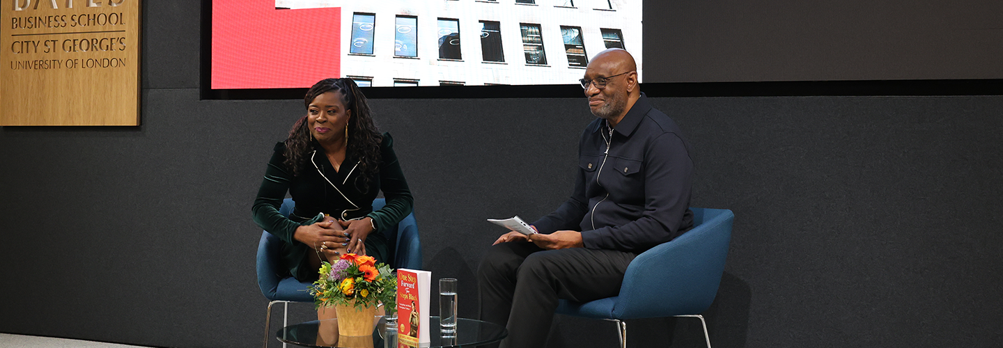 A man and woman sit on stage and smile
