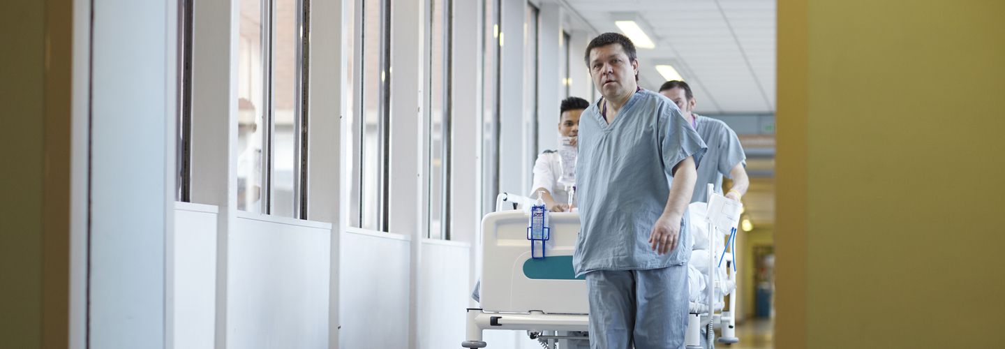 Hospital workers transporting patient on a gurney through a hospital corridor