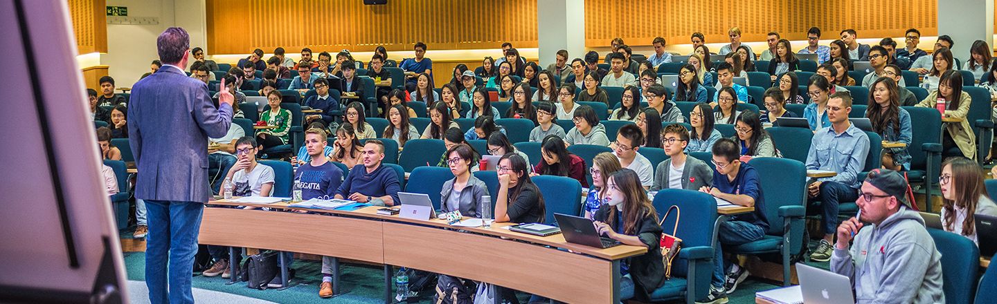 Male academic talking in a lecture to a room full of student