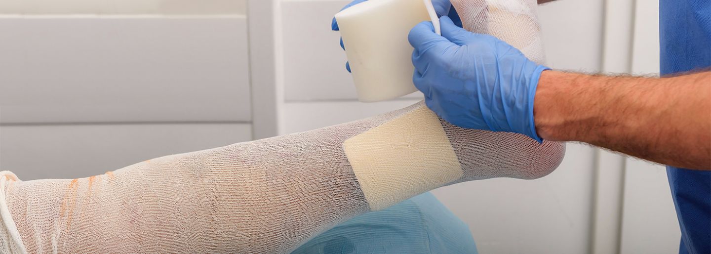 Male nurse putting medical bandage on foot of person