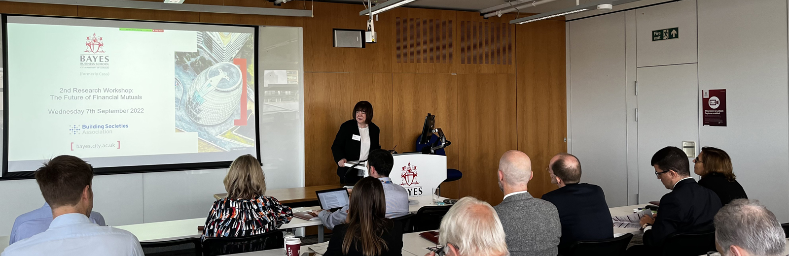 Dame Colette Bowe delivers her speech alongside a projector screen