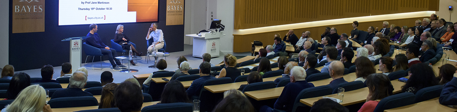 Professor Jane Martinson on the stage speaking with Kamal Ahmed and Sir William Lewis.