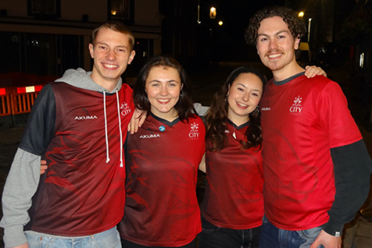 Four hockey co-captains (two men and two women) are smiling and standing together at a pub crawl