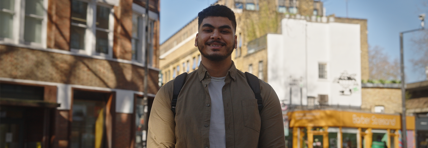 A man with short hair smiles outside 