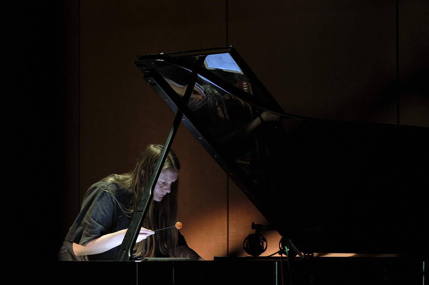 Woman performing percussion on the interior of a piano