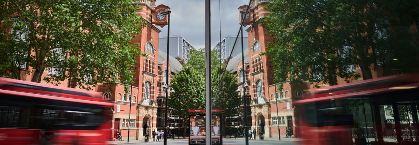 Rhind building with reflection of College building, buses and people.