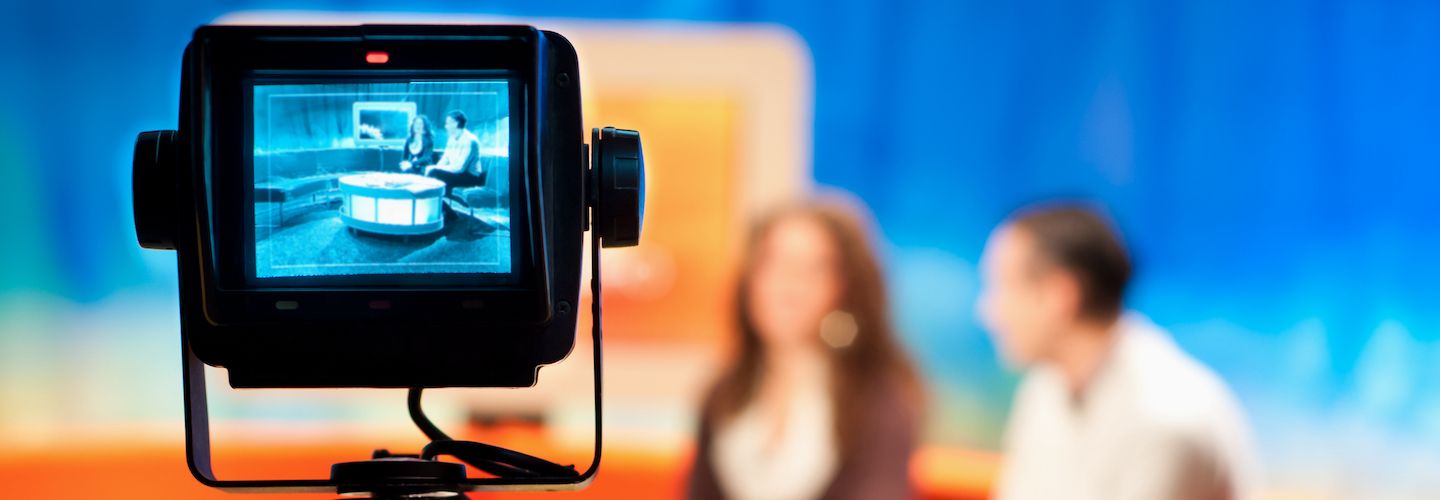 A camera recording a female and a male in a TV studio