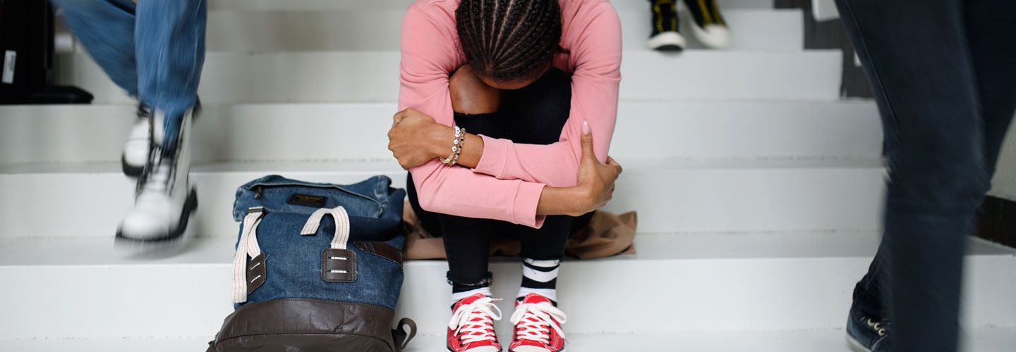 Young girl on school steps with head on knees
