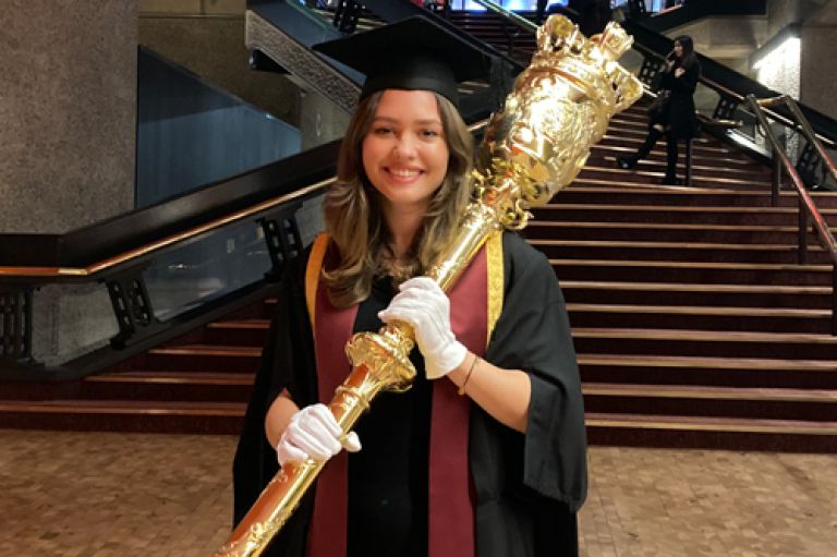 Student President Gesmina Tsourrai carries ceremonial mace at graduation