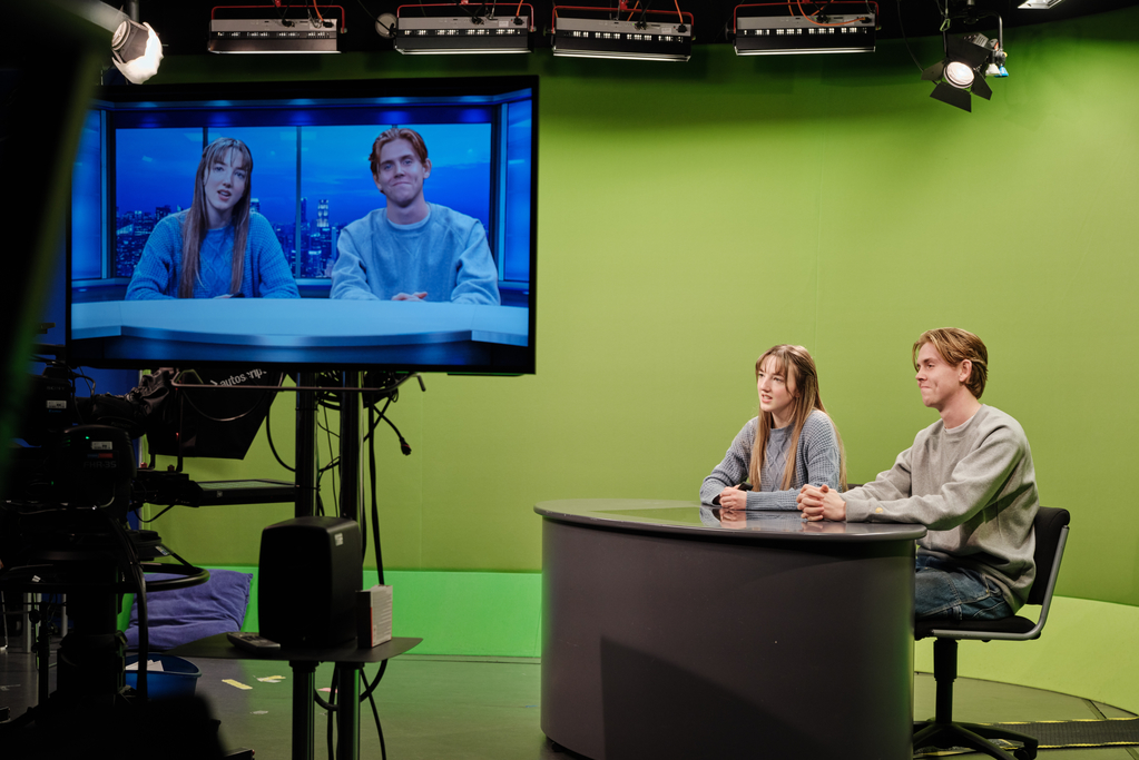 Two undergraduate students present to camera using the green screen 