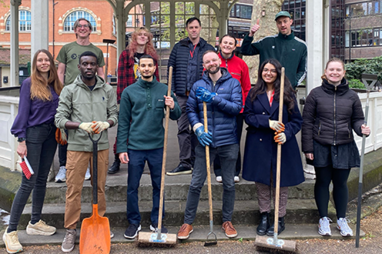 Volunteers at a gardening session in Northampton Square holding gardening tools and standing outside a bandstand