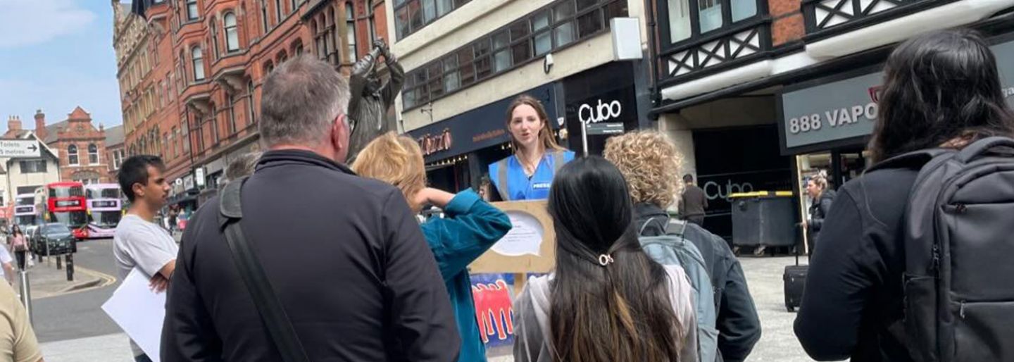 A group of people watch a student deliver news on the street live