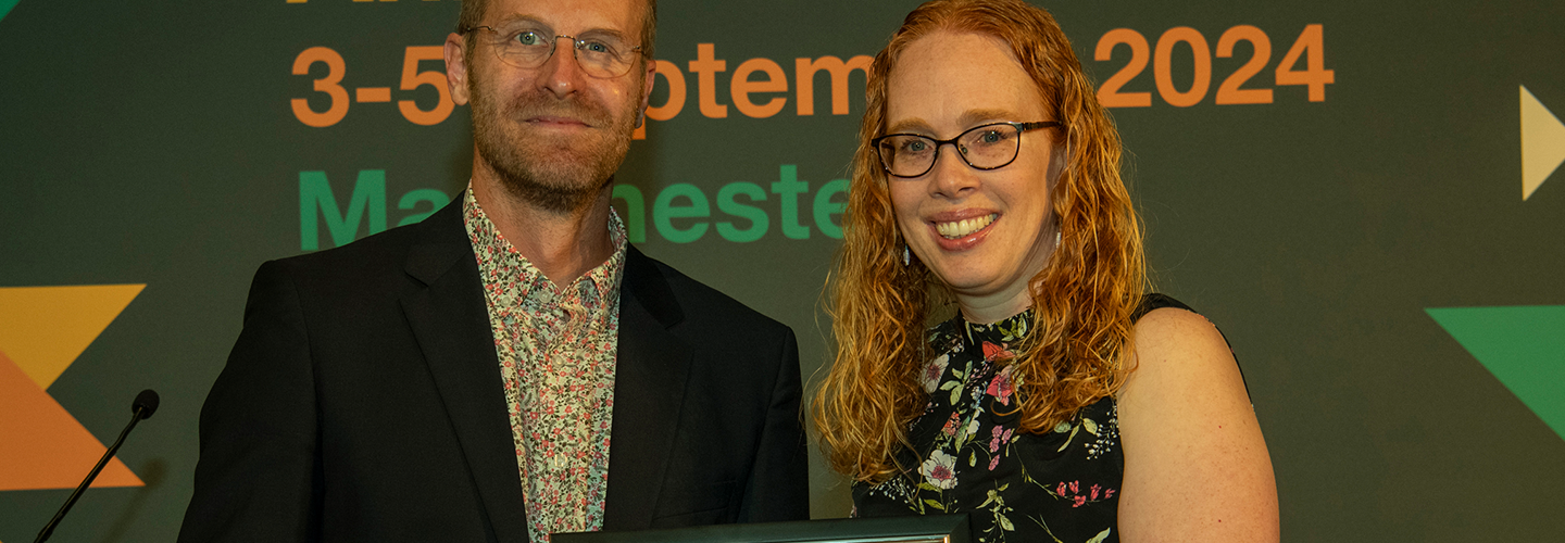 A man and woman hold a certificate and smile at an awards ceremony