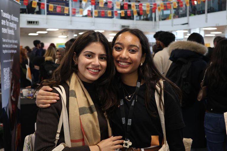 Two women smile at a Welcome event