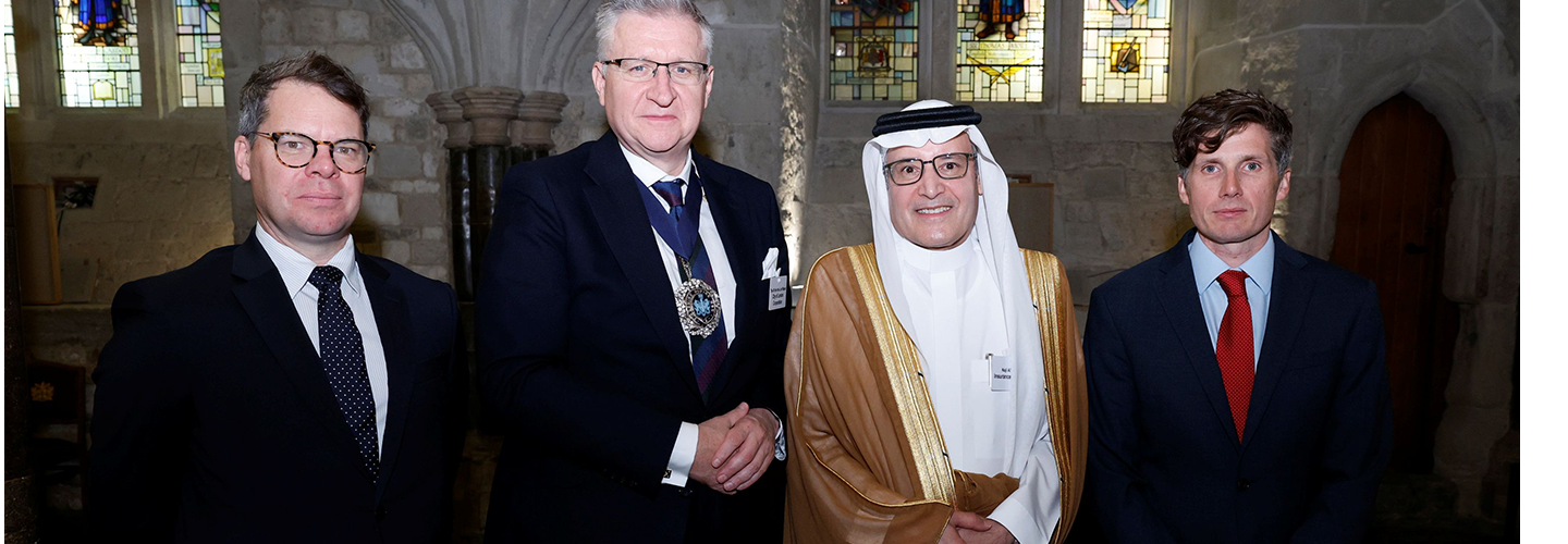 Three men in suits and a man in Saudi dress. One of the men in suits has a mayoral chain of office around his neck.