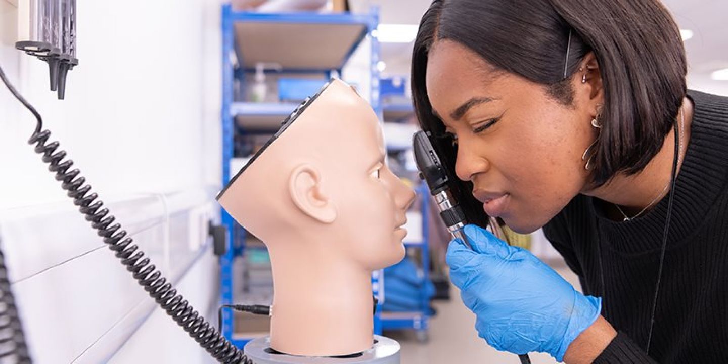 Students examining mannequin in clinical skills practice space