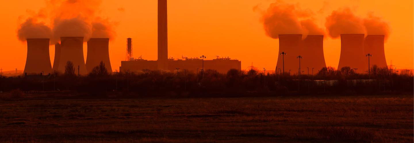 A power station belching steam into a golden sky