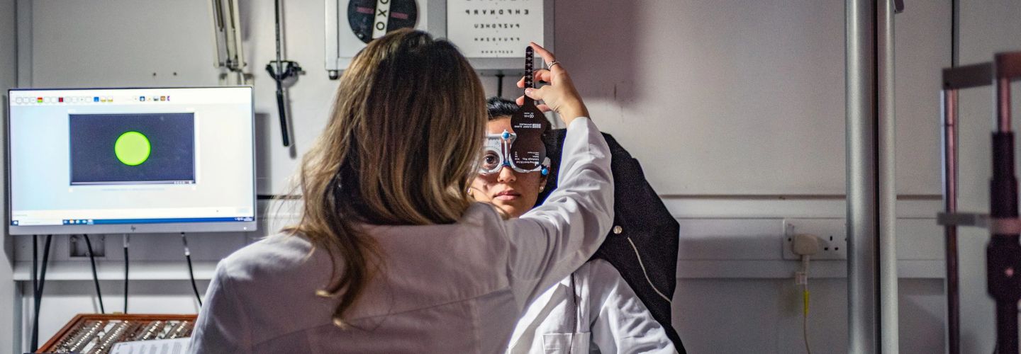 An optometrist is conducting an eye exam on a patient using specialised equipment.
