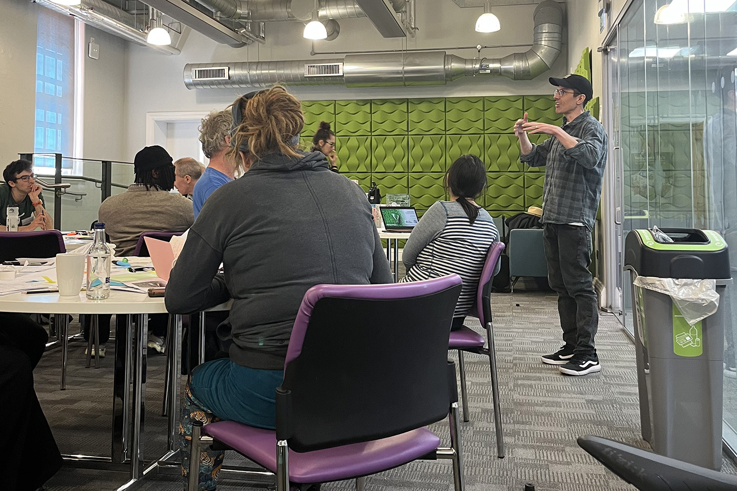 A man gestures as he presents to a workshop audience.