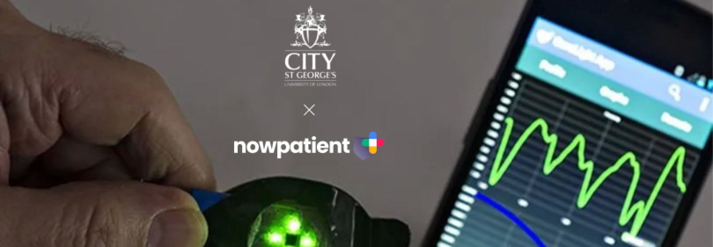 Hand holding a green-lit medical device next to a smartphone showing health data