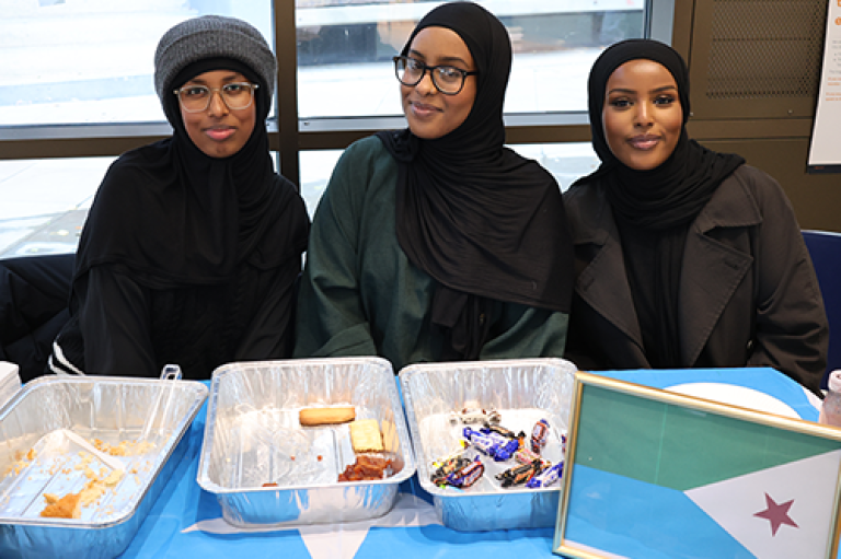 Three women pose for a photo at a stall