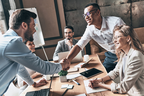 Smiling colleagues shaking hands in a boardroom